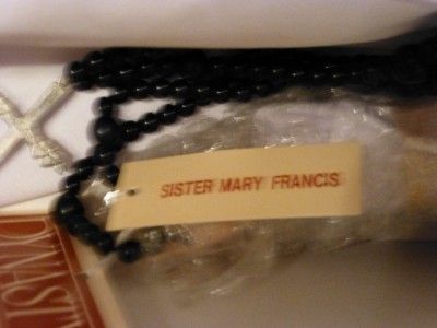 Sister Mary Francis has a beaded black rosary, is wearing glasses, has